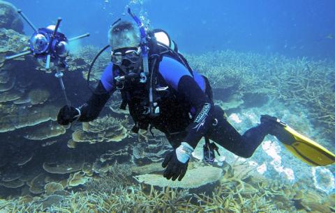 Scuba diver hovering over a reef holding a camera